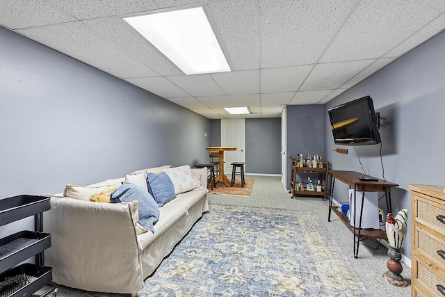 living room featuring a drop ceiling and carpet