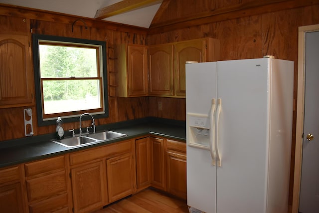 kitchen with lofted ceiling, sink, white refrigerator with ice dispenser, and light hardwood / wood-style flooring