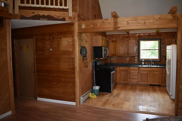 kitchen featuring wood walls, wood-type flooring, sink, stainless steel appliances, and baseboard heating