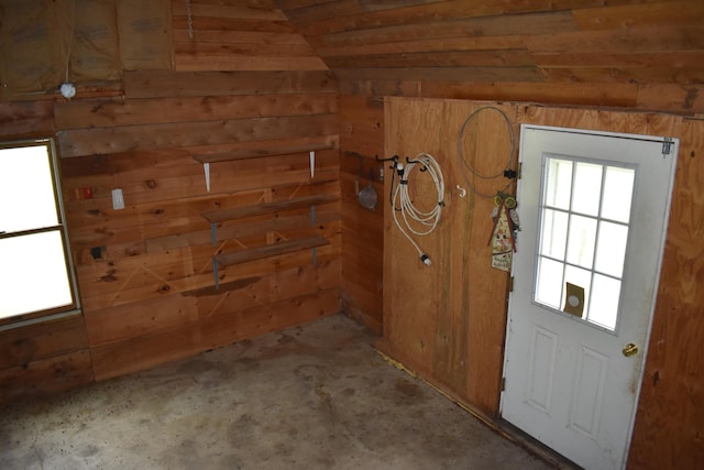 doorway with vaulted ceiling and wood walls