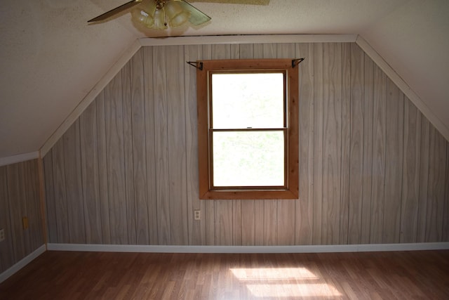 bonus room with lofted ceiling and wooden walls