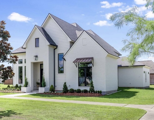 modern inspired farmhouse featuring roof with shingles and a front lawn