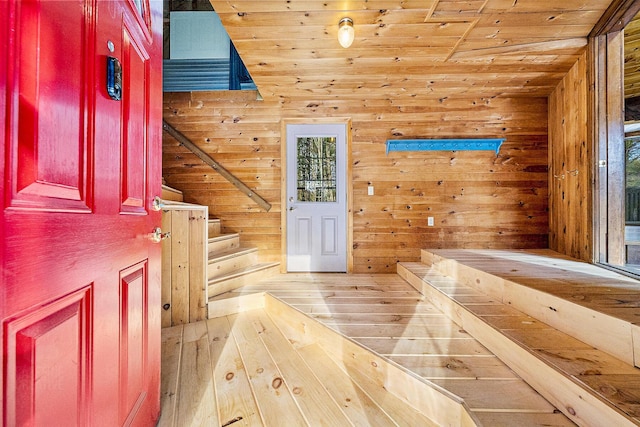 entryway with wooden ceiling, wood walls, and light hardwood / wood-style flooring