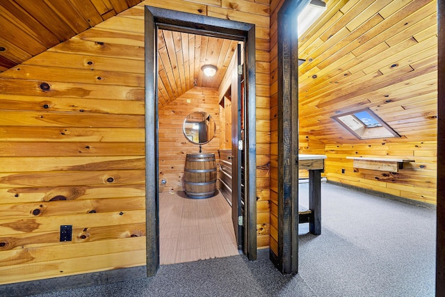 hallway featuring wooden walls, carpet, vaulted ceiling with skylight, and wood ceiling