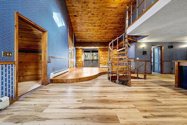 interior space with high vaulted ceiling, wood walls, a baseboard radiator, and light hardwood / wood-style floors