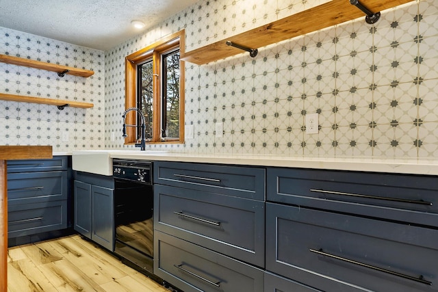 kitchen with a textured ceiling, light hardwood / wood-style floors, black dishwasher, and sink