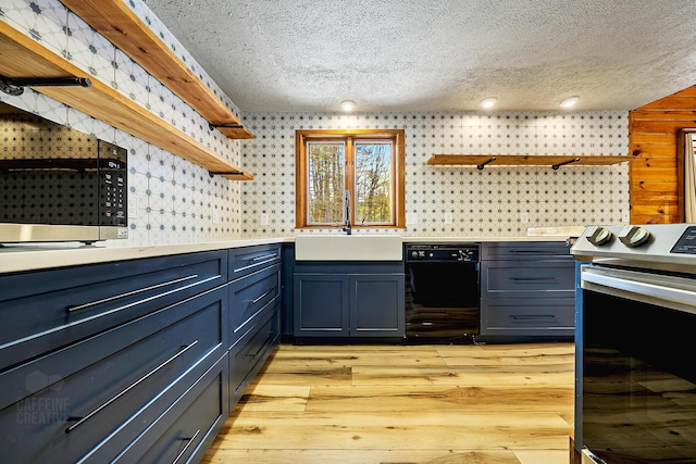 kitchen with sink, a textured ceiling, light wood-type flooring, blue cabinetry, and appliances with stainless steel finishes