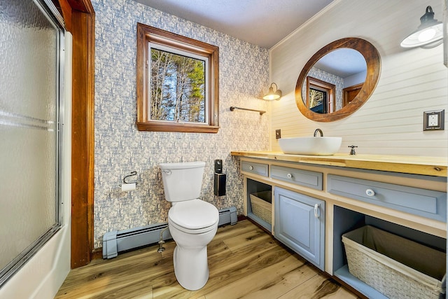 full bathroom featuring toilet, baseboard heating, combined bath / shower with glass door, and hardwood / wood-style floors