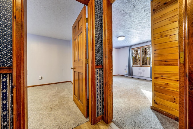 hall featuring a textured ceiling and light colored carpet