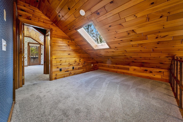 additional living space featuring carpet flooring, wood walls, lofted ceiling with skylight, and wood ceiling