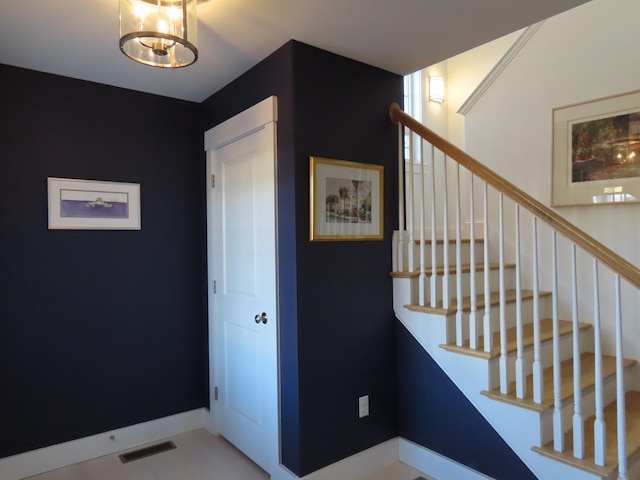 stairs with a notable chandelier and tile patterned floors