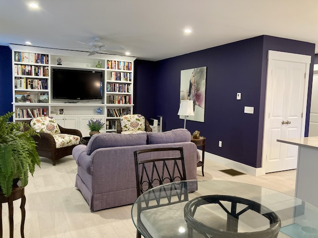 living room with built in shelves, ceiling fan, and light hardwood / wood-style flooring