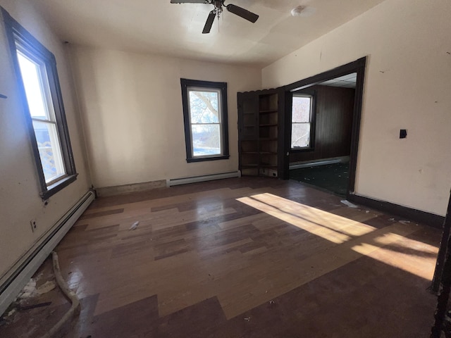 unfurnished room with ceiling fan, dark wood-type flooring, and a baseboard heating unit