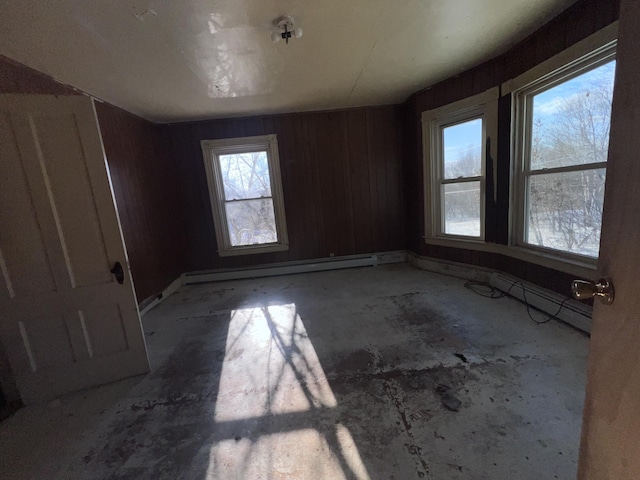 empty room featuring baseboard heating and wooden walls