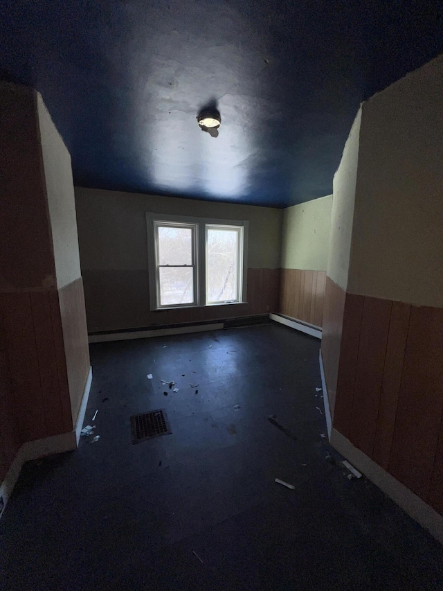 bonus room with a baseboard heating unit and wooden walls