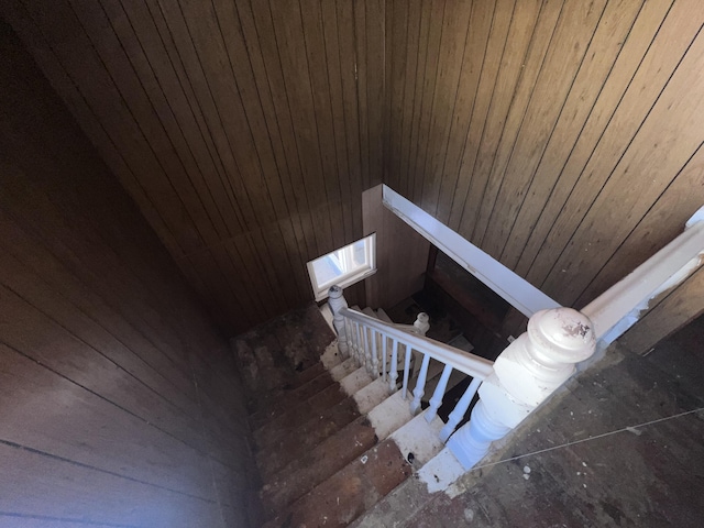 stairway featuring wooden walls