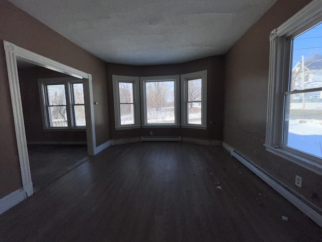 spare room with dark hardwood / wood-style flooring, a textured ceiling, and a baseboard radiator