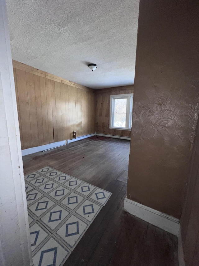 unfurnished room with dark hardwood / wood-style floors, wood walls, and a textured ceiling