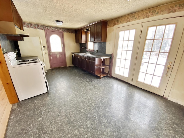 kitchen with electric range, a textured ceiling, a healthy amount of sunlight, and sink