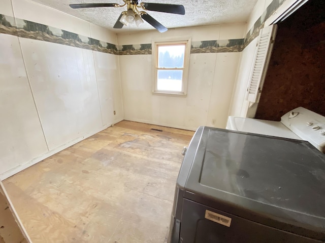 laundry room featuring separate washer and dryer, ceiling fan, and a textured ceiling