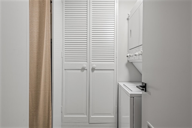 laundry area featuring stacked washer and dryer and cabinets