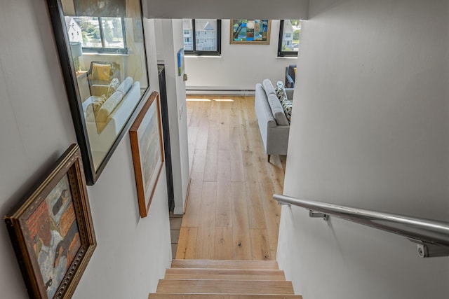 staircase featuring plenty of natural light, hardwood / wood-style flooring, and a baseboard radiator