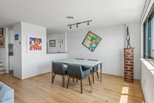 dining area featuring track lighting and light hardwood / wood-style flooring