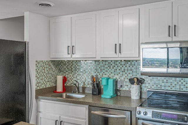 kitchen with appliances with stainless steel finishes, decorative backsplash, white cabinetry, and sink