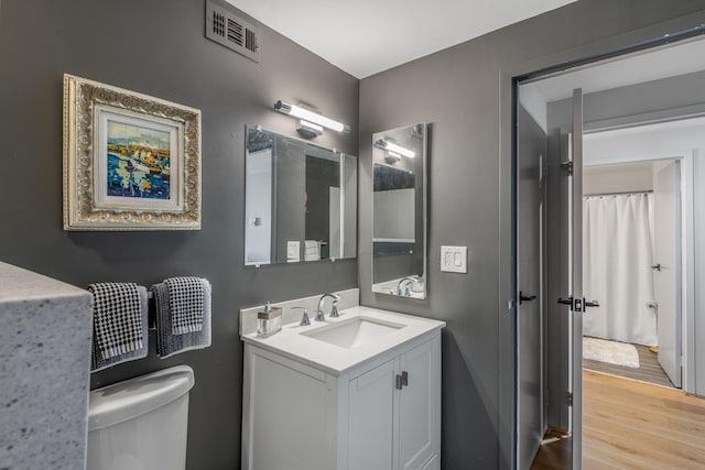 bathroom with hardwood / wood-style floors, toilet, and vanity