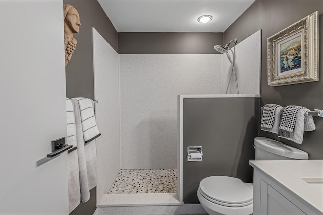 bathroom featuring toilet, vanity, and a tile shower