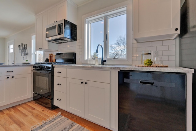 kitchen with white cabinets, black appliances, tasteful backsplash, and light hardwood / wood-style flooring