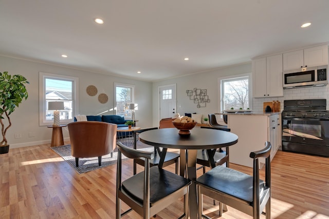 dining area featuring light wood-type flooring and crown molding