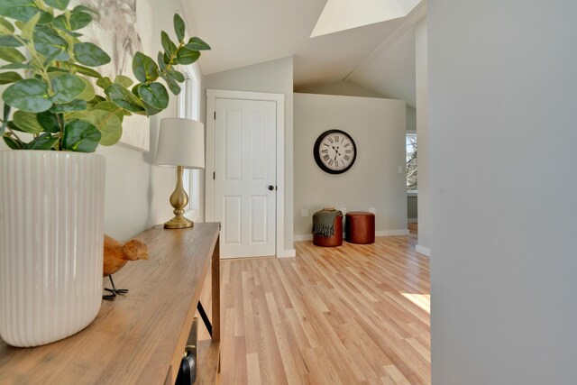 interior space with hardwood / wood-style floors and vaulted ceiling with skylight