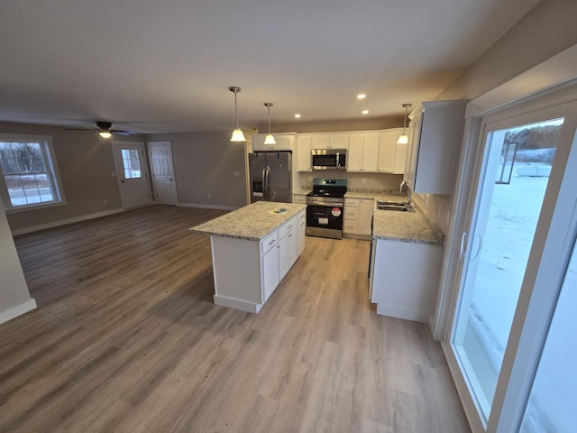 kitchen featuring a center island, sink, hanging light fixtures, appliances with stainless steel finishes, and white cabinets