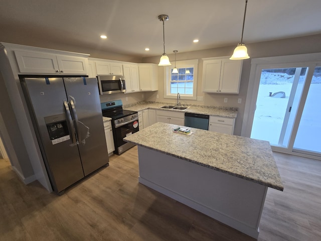 kitchen with decorative light fixtures, white cabinets, stainless steel appliances, and a kitchen island