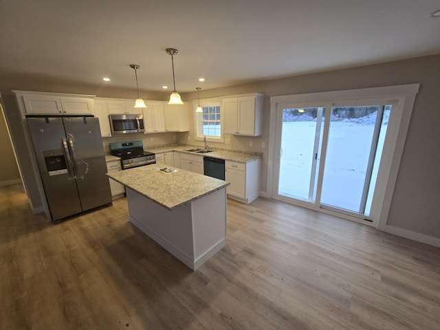 kitchen with a kitchen island, sink, white cabinetry, hanging light fixtures, and stainless steel appliances