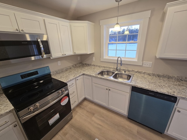 kitchen with appliances with stainless steel finishes, light hardwood / wood-style floors, white cabinetry, and sink