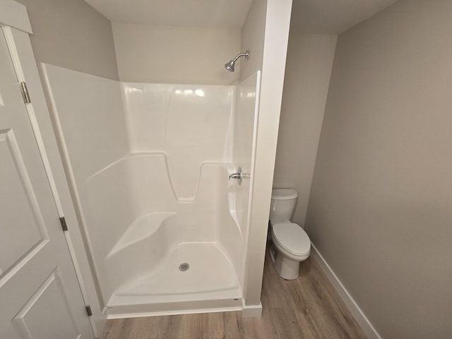 bathroom featuring toilet, wood-type flooring, and a shower