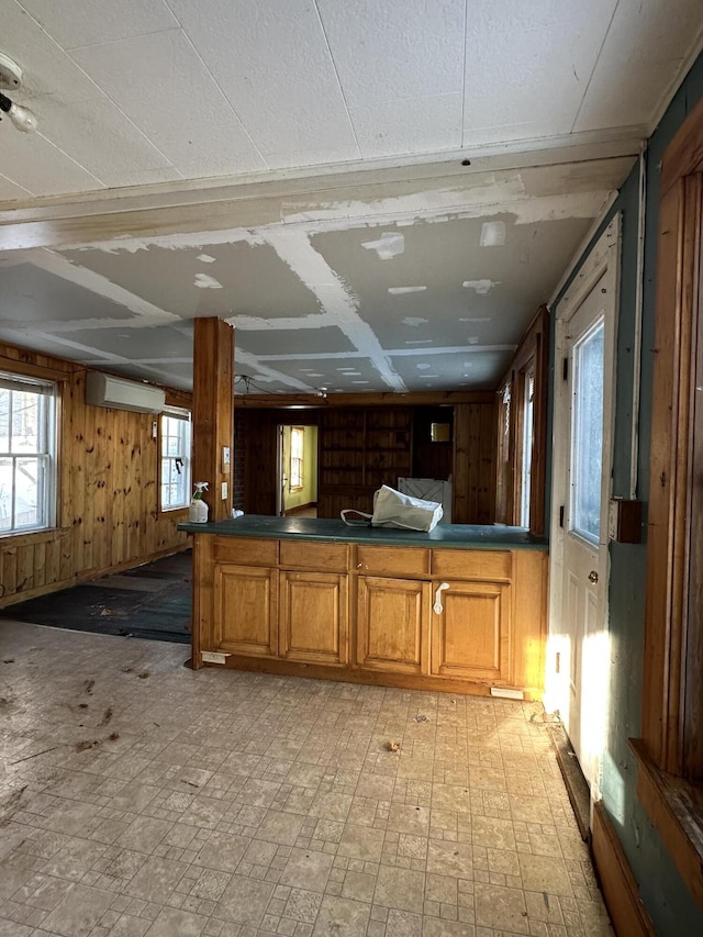 kitchen with a wall mounted air conditioner, wooden walls, and kitchen peninsula