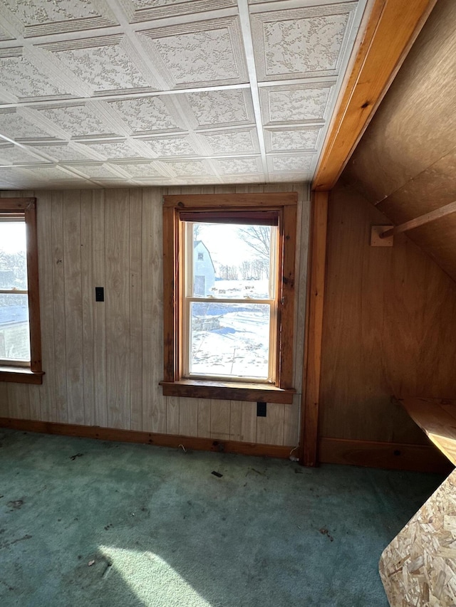 bonus room with carpet flooring and wood walls