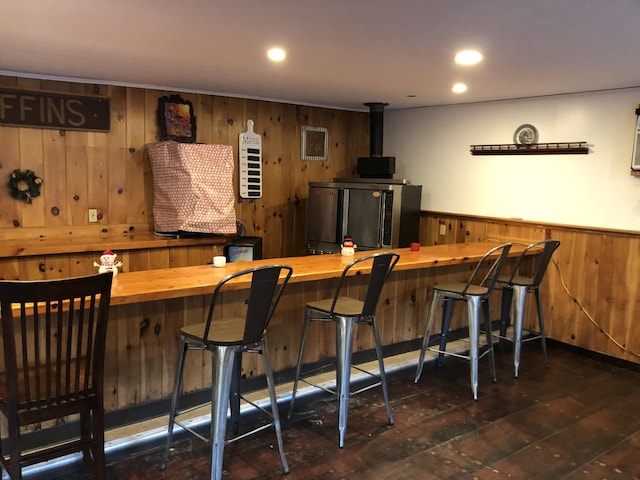 bar featuring stainless steel fridge, wood walls, dark wood-type flooring, and butcher block counters