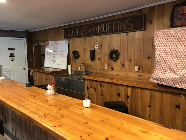 bar featuring wooden counters, wood walls, and sink