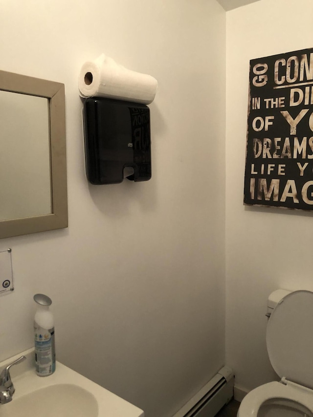 bathroom featuring toilet, a baseboard heating unit, and sink