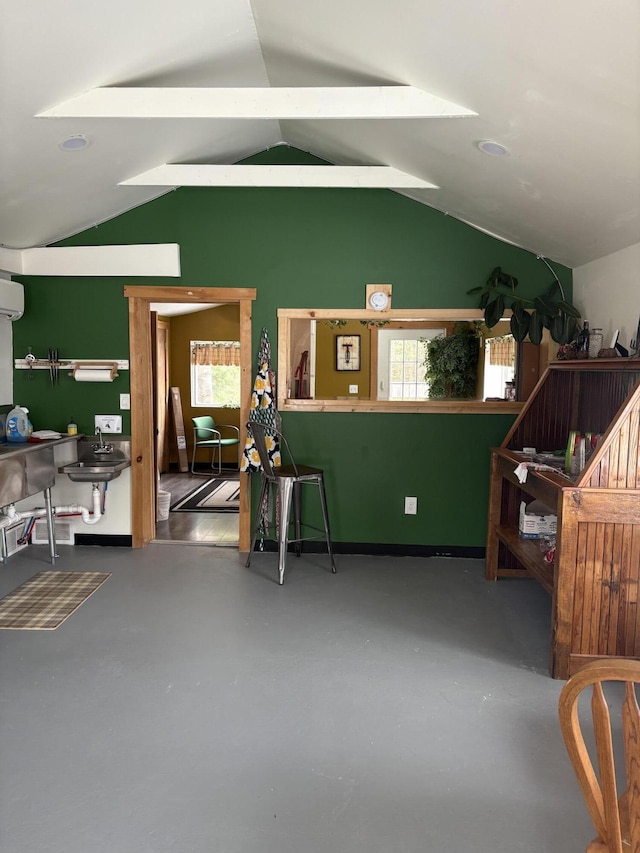 interior space featuring lofted ceiling, an AC wall unit, a healthy amount of sunlight, and sink