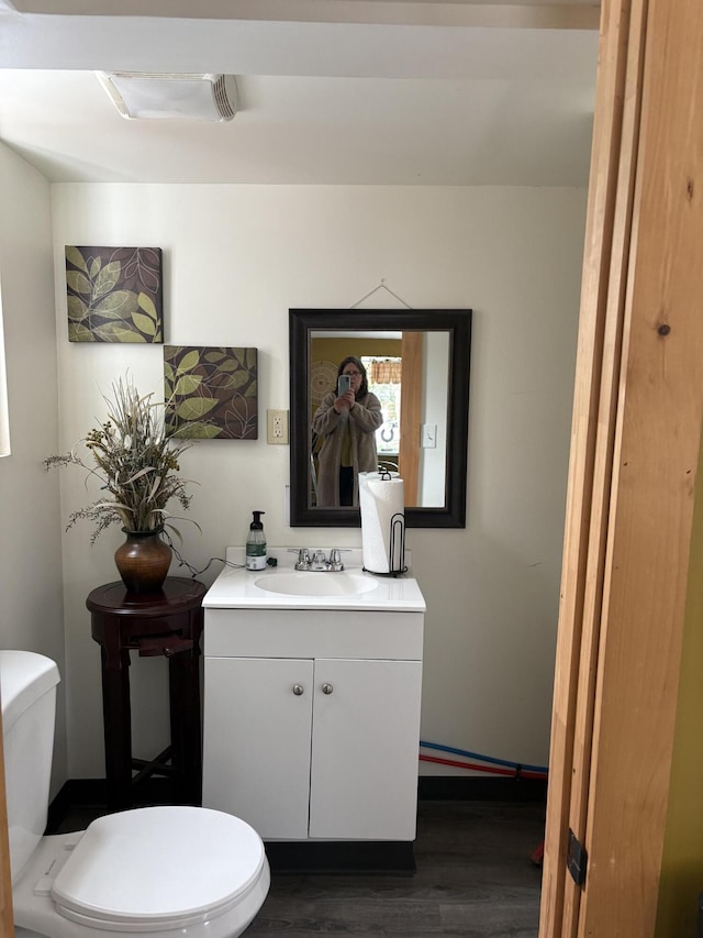 bathroom featuring toilet, vanity, and hardwood / wood-style flooring