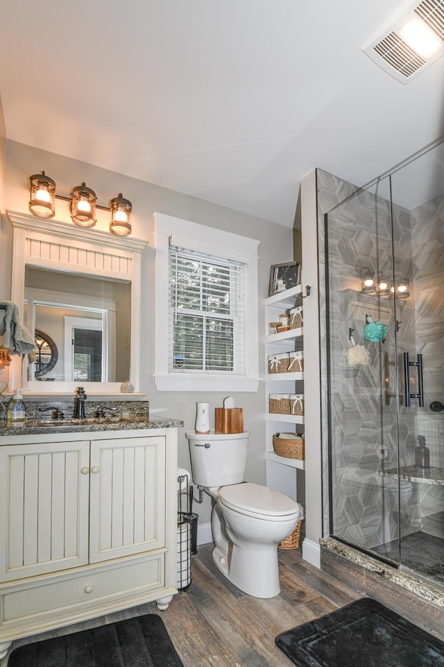 bathroom featuring toilet, a shower with shower door, hardwood / wood-style floors, and vanity