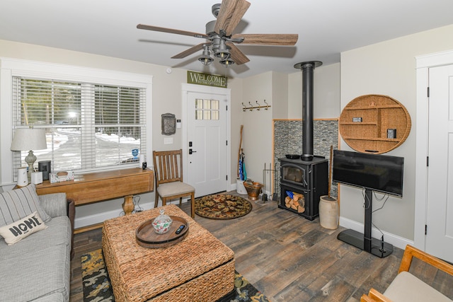 living room with ceiling fan, a wood stove, and dark hardwood / wood-style floors