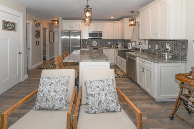 kitchen featuring a center island, pendant lighting, sink, dark wood-type flooring, and stainless steel appliances