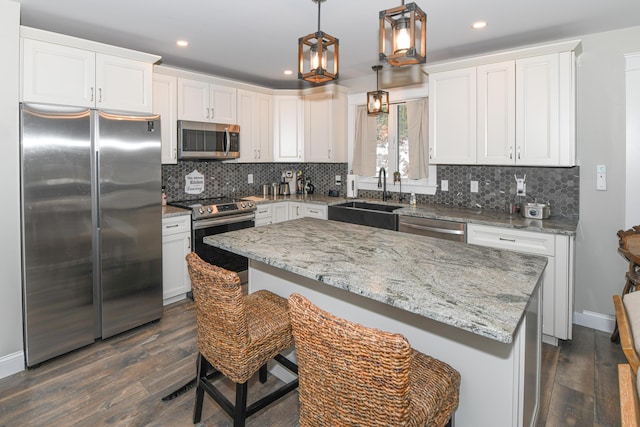 kitchen with stainless steel appliances, white cabinetry, decorative light fixtures, and sink