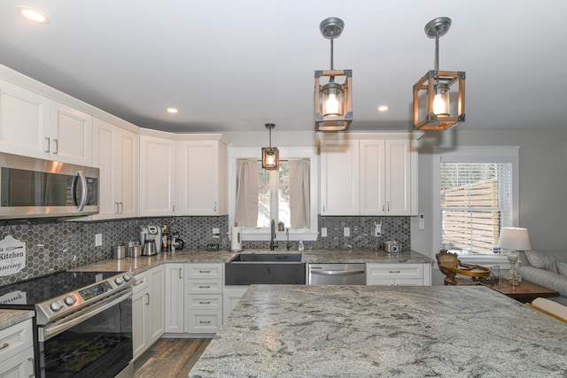 kitchen featuring appliances with stainless steel finishes, sink, white cabinetry, and decorative light fixtures